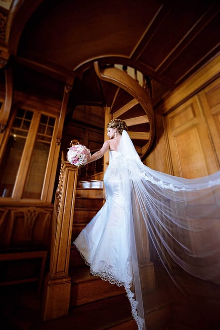 Beauty bride in bridal gown with bouquet and lace veil indoors