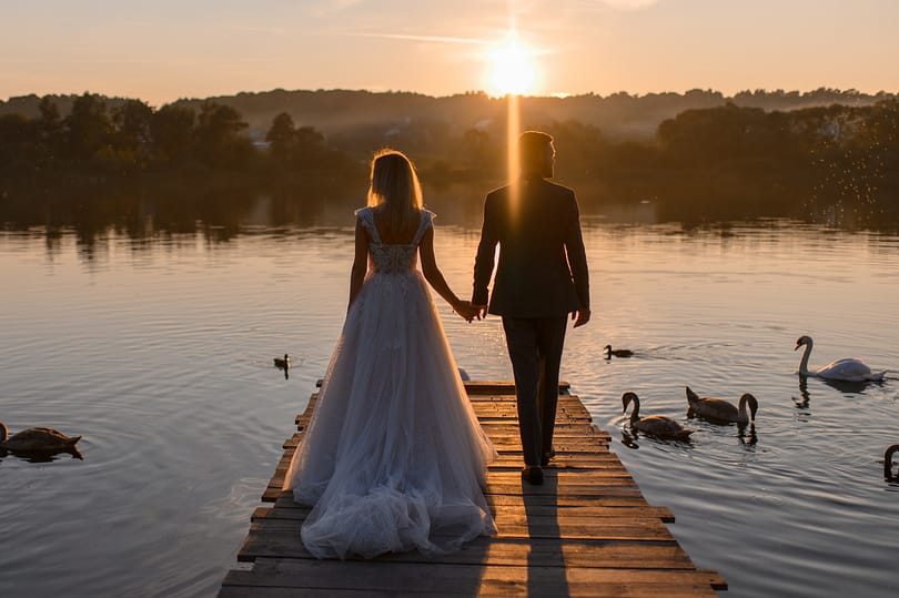 The bride and groom are in the back at sunset