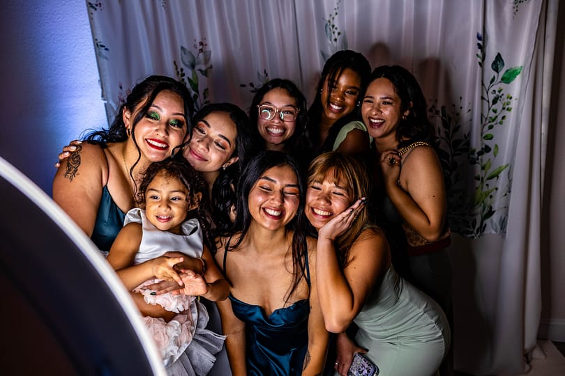 young ladies pose for a group photograph with an adult and young child