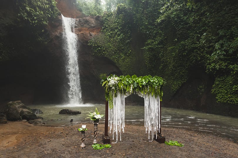 Tropical wedding ceremony with waterfall view. White arch decora