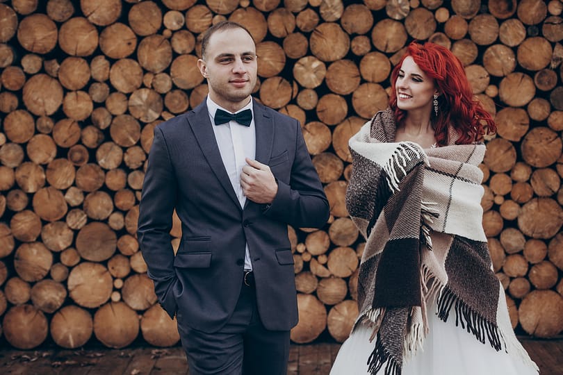 Wedding couple embracing in sunlight at background of wooden fir