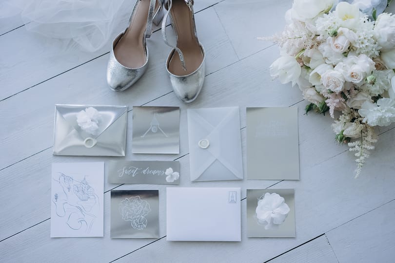 top view of wedding invitations with bridal shoes and bouquet on floor